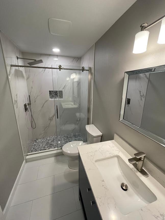 Bathroom remodel with glass shower, vanity, and marble-look wall tile