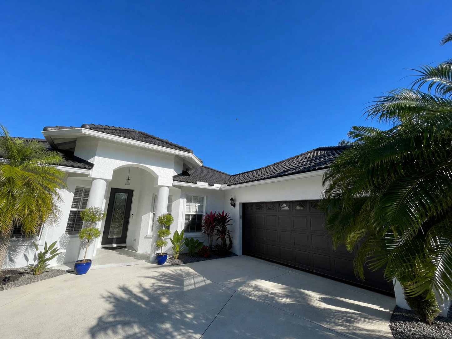 Completed exterior painting project with white home and garage